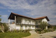 A two-storey house with a red tiled roof, painted white façade and light green shutters | © Alessandro Santi