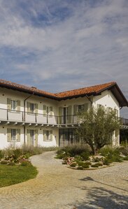 A two-storey house with a red tiled roof, painted white façade and light green shutters | © Alessandro Santi