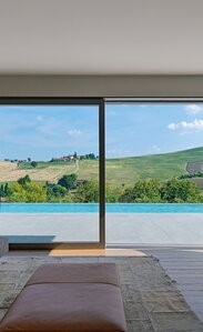 Ausblick aus einem Wohnzimmer auf einen Swimmingpoos und grüne Hügel | © Matteo Piazza