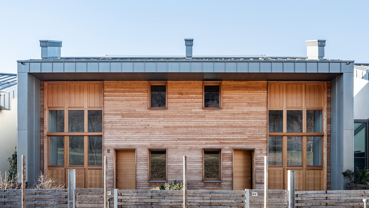 Ein Wohnhaus mit einer Fassade aus Lärchenholz und Titanzinkim Vordergrund ein Holzzaun | © Andrea Ceriani