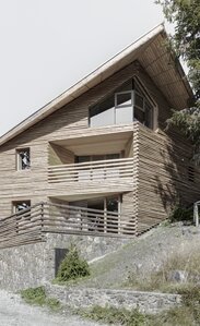 Ein Gebäude mit einem Sockel aus Naturstein und einer Fassadenverkleidung aus geviertelten Baumstämmen | © Gustav Willeit
